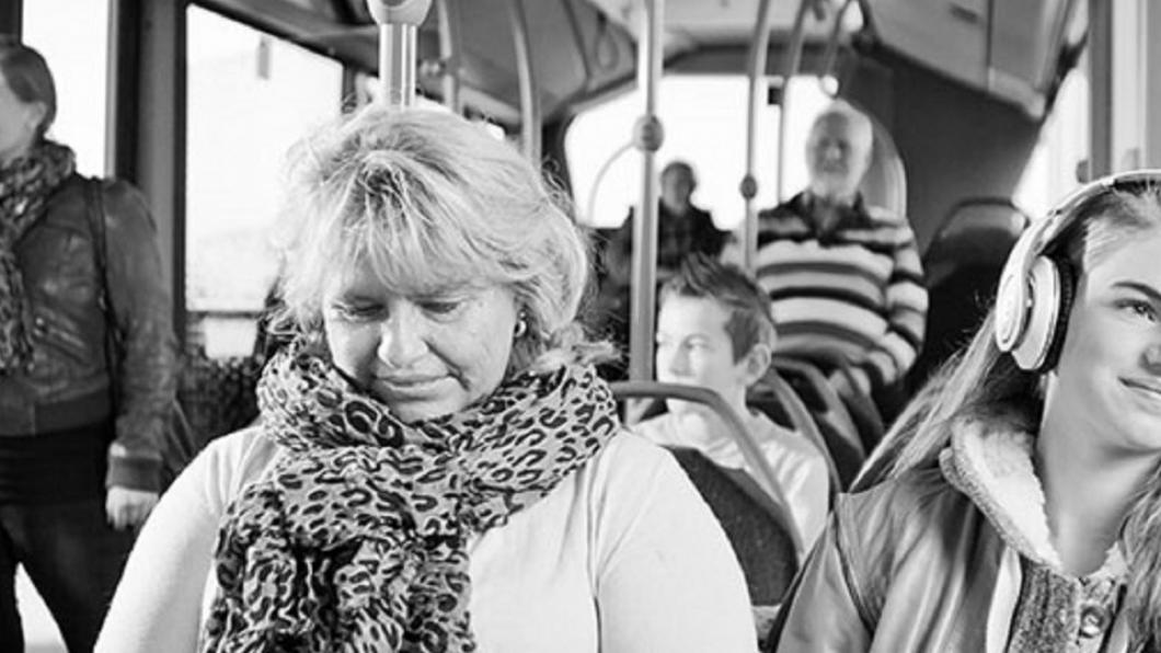 Een zwart-wit foto van de binnenkant van een bus, met meerdere inzittenden.