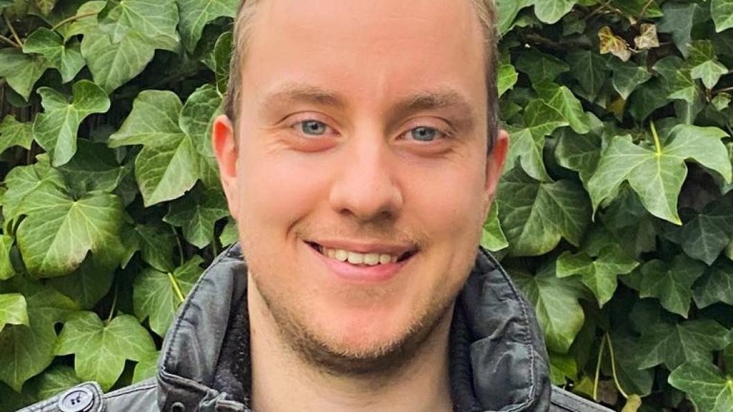Foto van Rick, een grijze jas dragende, met op de achtergrond een heg.