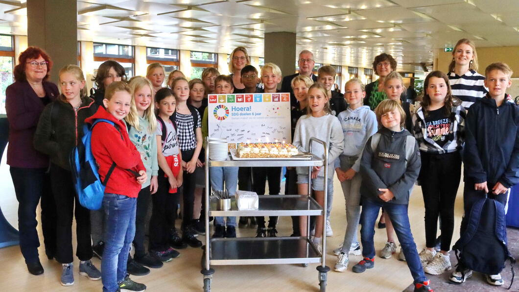 Foto van basisschoolleerlingen die de SDG-vlag uitreiken