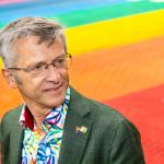 Foto van Henk Nijmeijer op een "gaybrapad", een zebrapad in de kleuren van de regenboog.