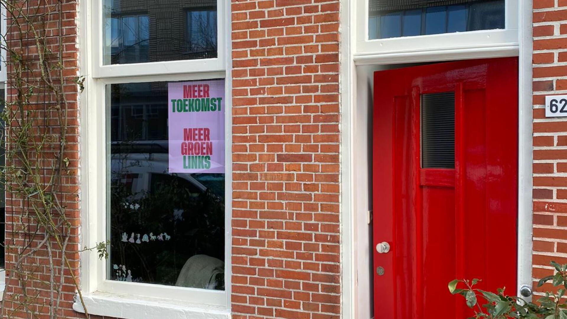 Foto van de voorkant van een huis, met een GroenLinks-poster achter het raam geplakt.
