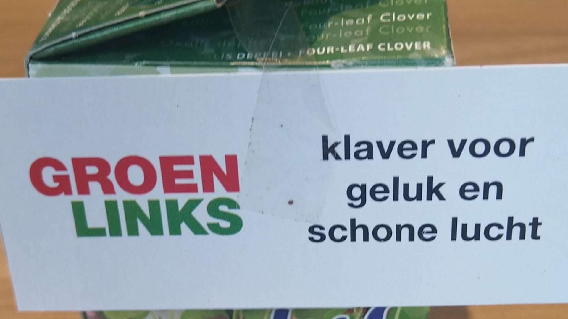 Foto van een doosje met een klavertje vier erin, met hierop een papiertje met het GroenLinks-logo en de tekst "klaver voor geluk en schone lucht"