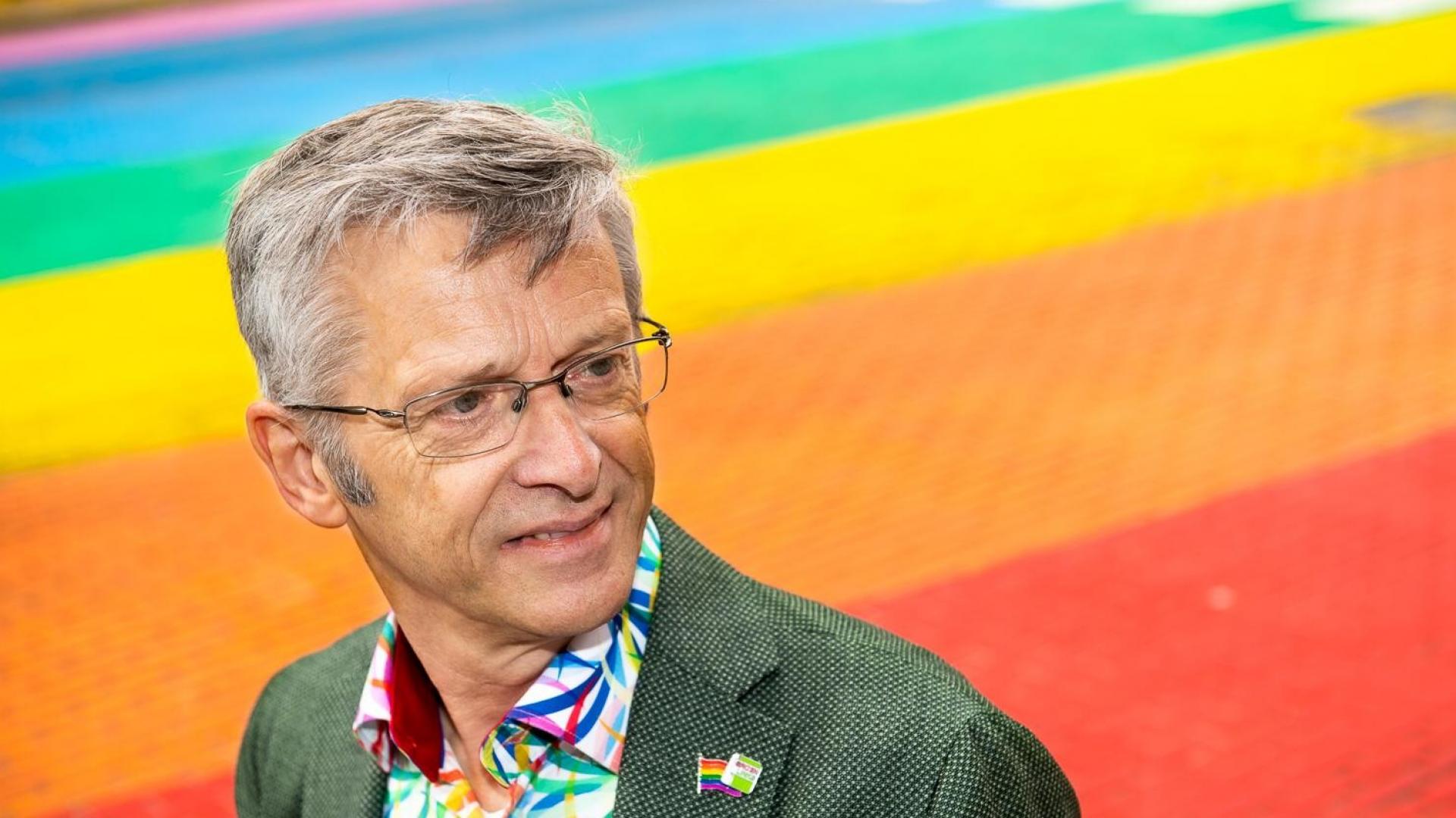 Foto van Henk Nijmeijer op een "gaybrapad", een zebrapad in de kleuren van de regenboog.
