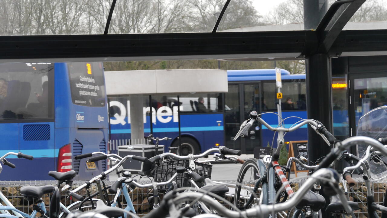 Foto van fietsen op een bushalte, met de Q-Liner bus op de achtergrond.